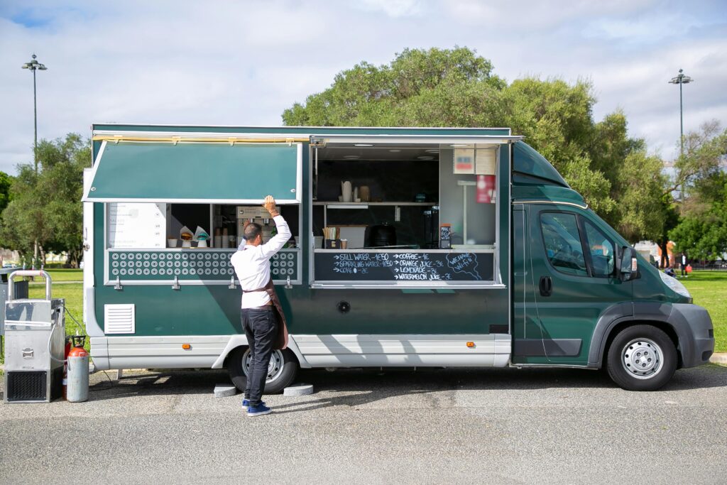 negócio Back view full body of anonymous male worker opening windows of car with street food parked in park
